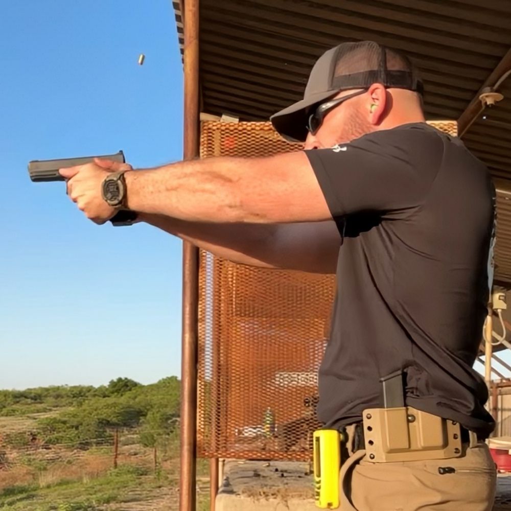 Summit Defense instructor demonstrating handgun shooting at an outdoor range
