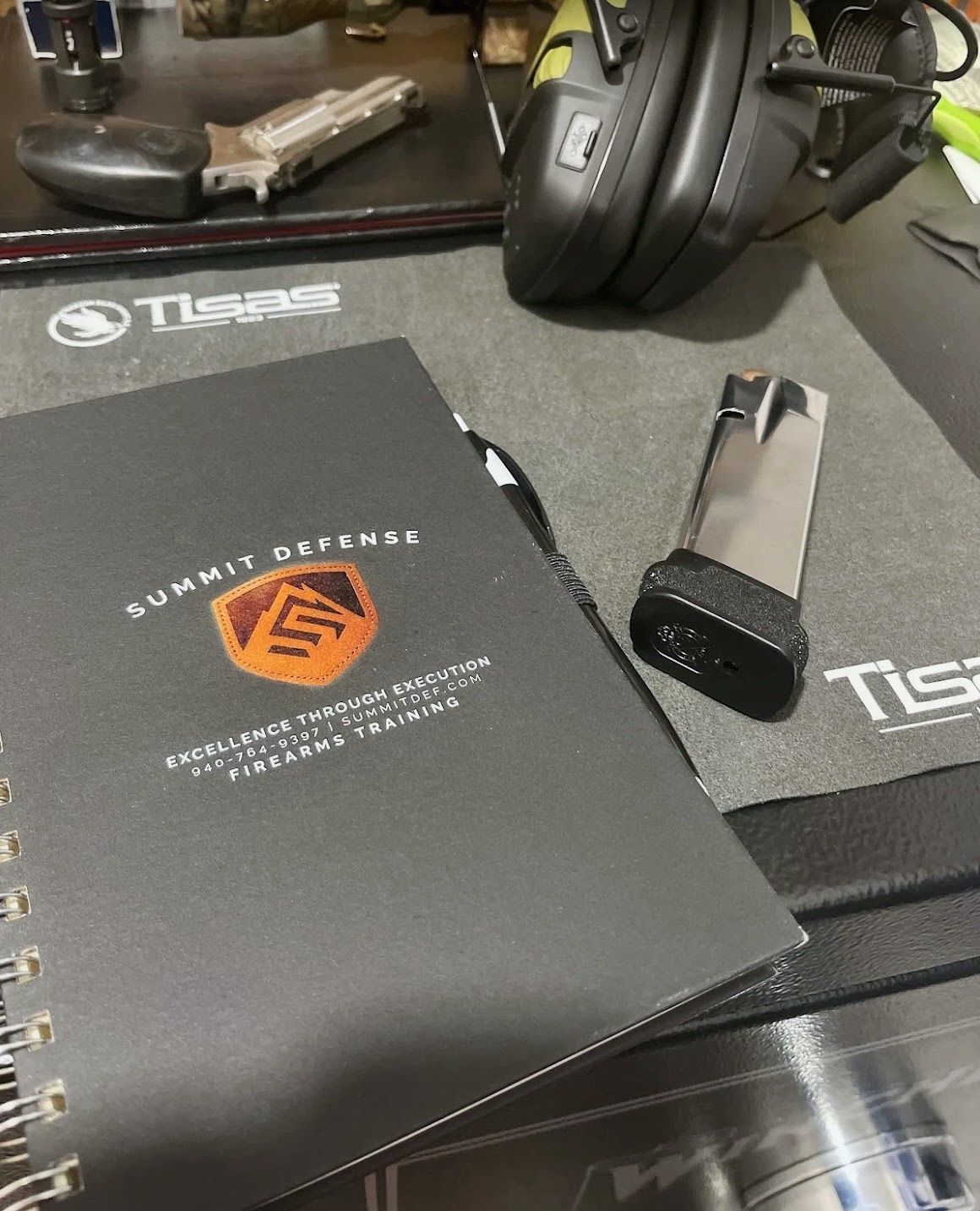 Summit Defense training notebook, handgun magazine, and hearing protection prepared for a firearms session
