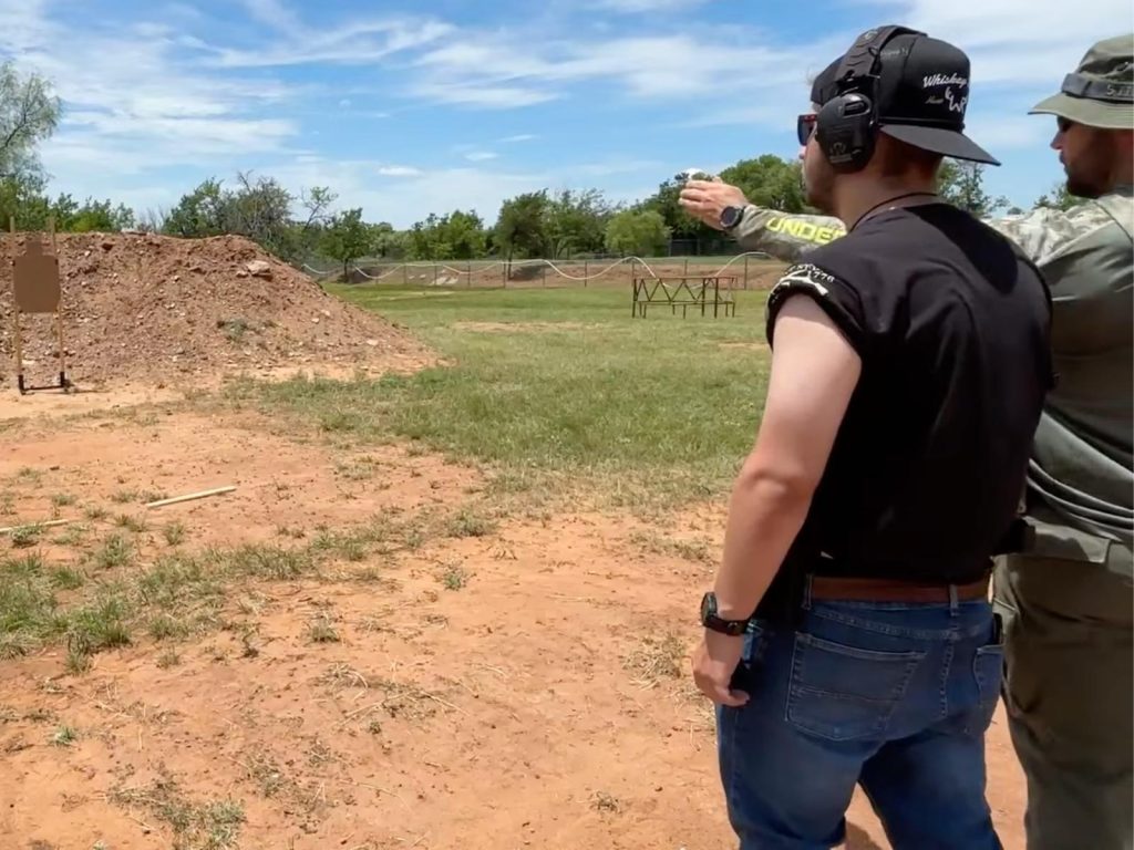 Instructor coaching a student during private handgun training at an outdoor range